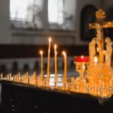Morminte îngrijite într-un cimitir de sat, cu lumânări aprinse și flori proaspete așezate pe cruci