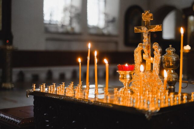 Morminte îngrijite într-un cimitir de sat, cu lumânări aprinse și flori proaspete așezate pe cruci
