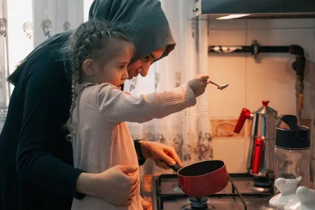Trei generații discută la masa din bucătărie, cu ceai și un caiet deschis