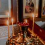 Lumânări aprinse într-un sfeșnic de biserică ortodoxă, într-o lumină caldă și liniștită