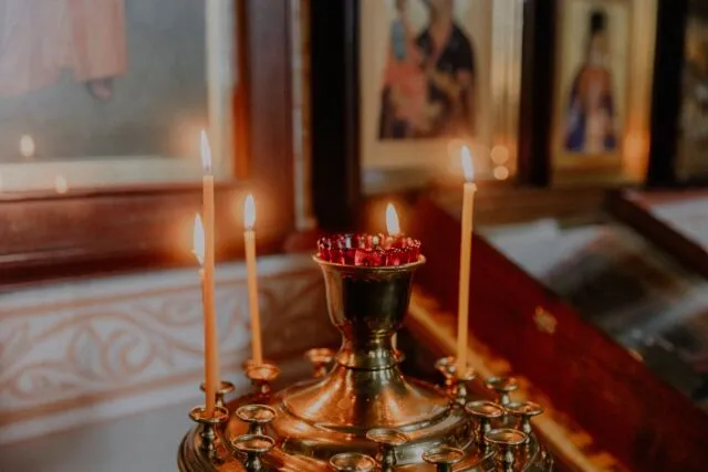 Lumânări aprinse într-un sfeșnic de biserică ortodoxă, într-o lumină caldă și liniștită